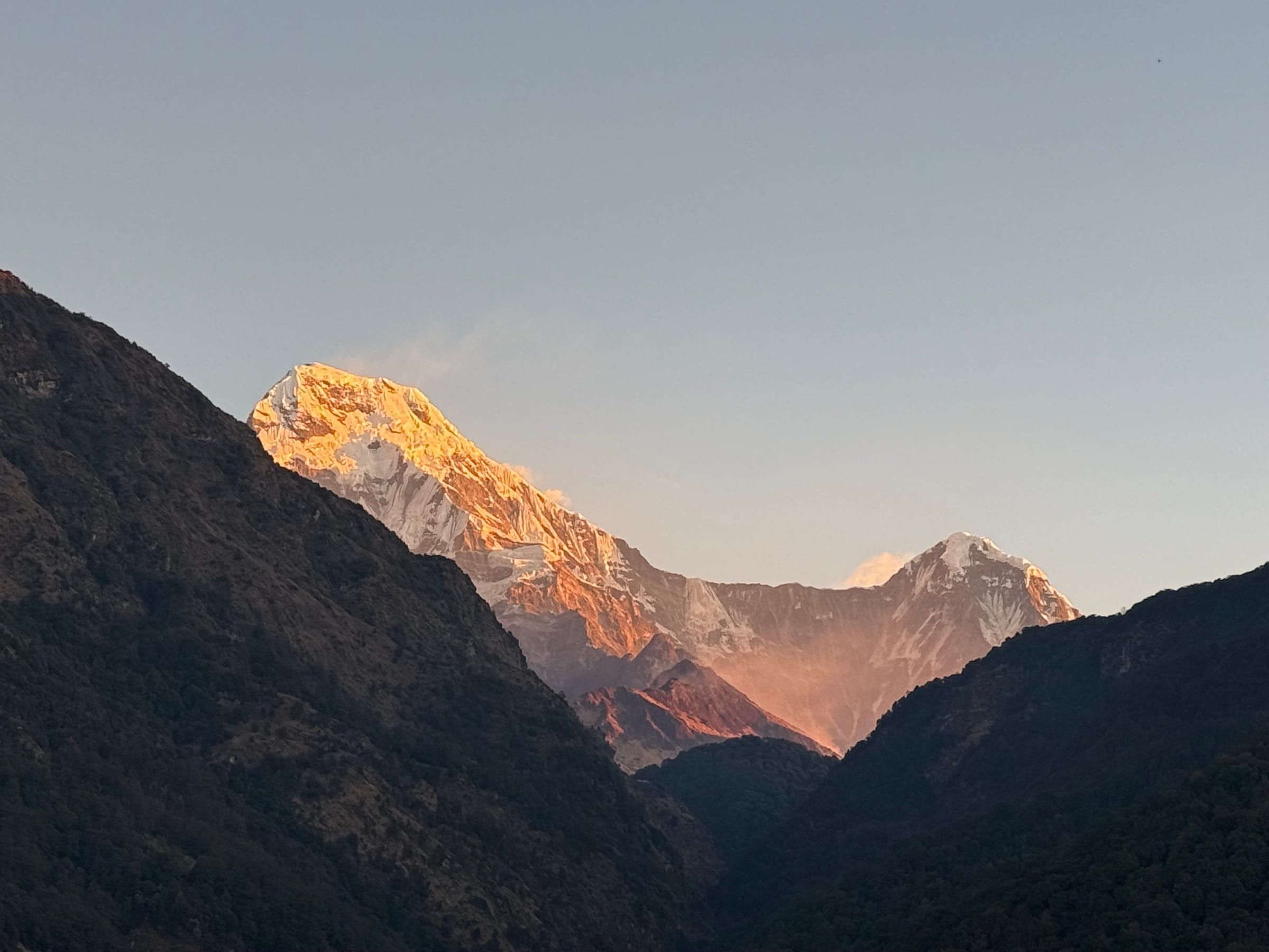 A dawn-lit peak glowing gold against a still-dark ridge below