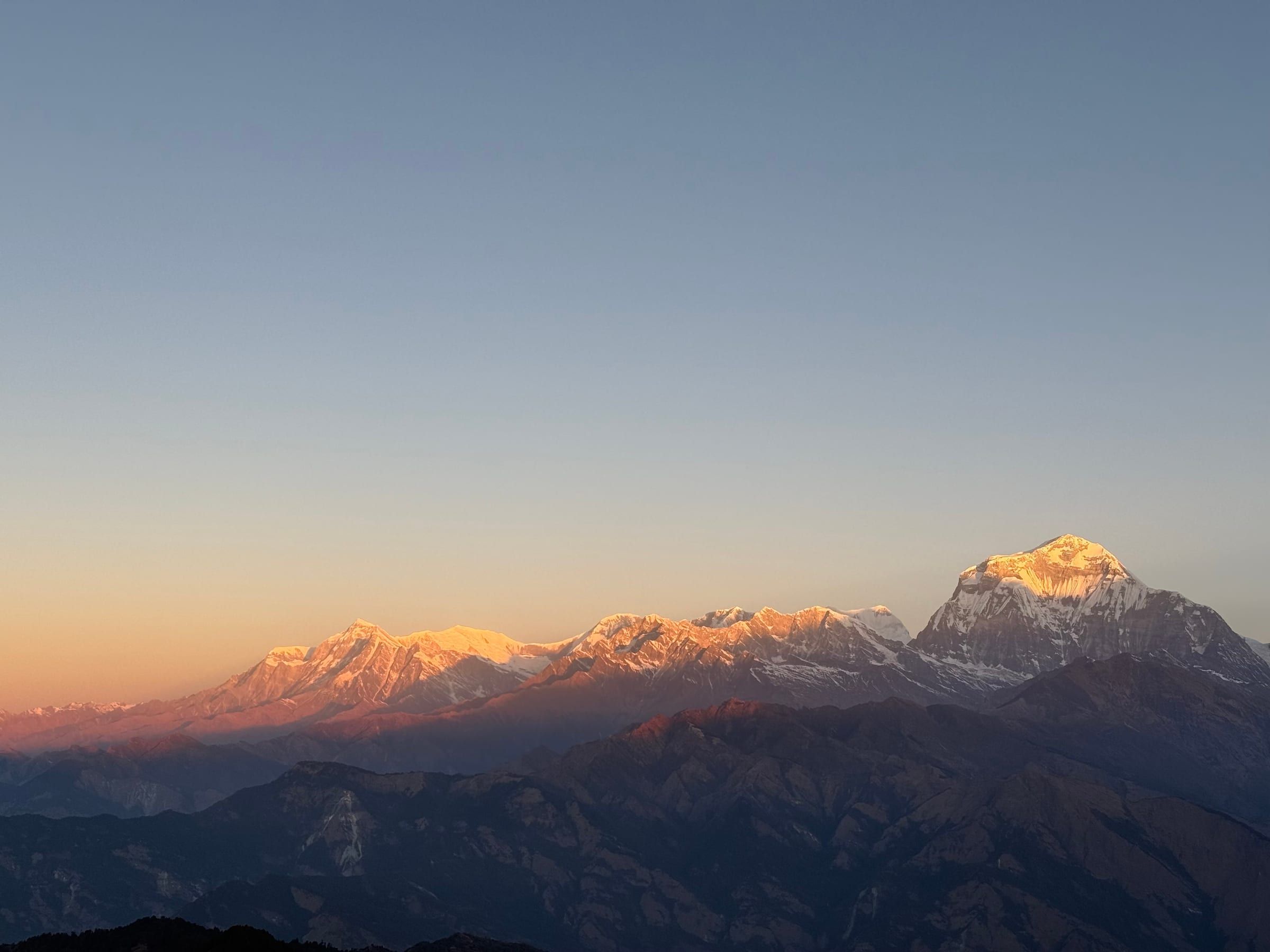 Wide sunset view of a golden mountain ridge, snow catching the last light