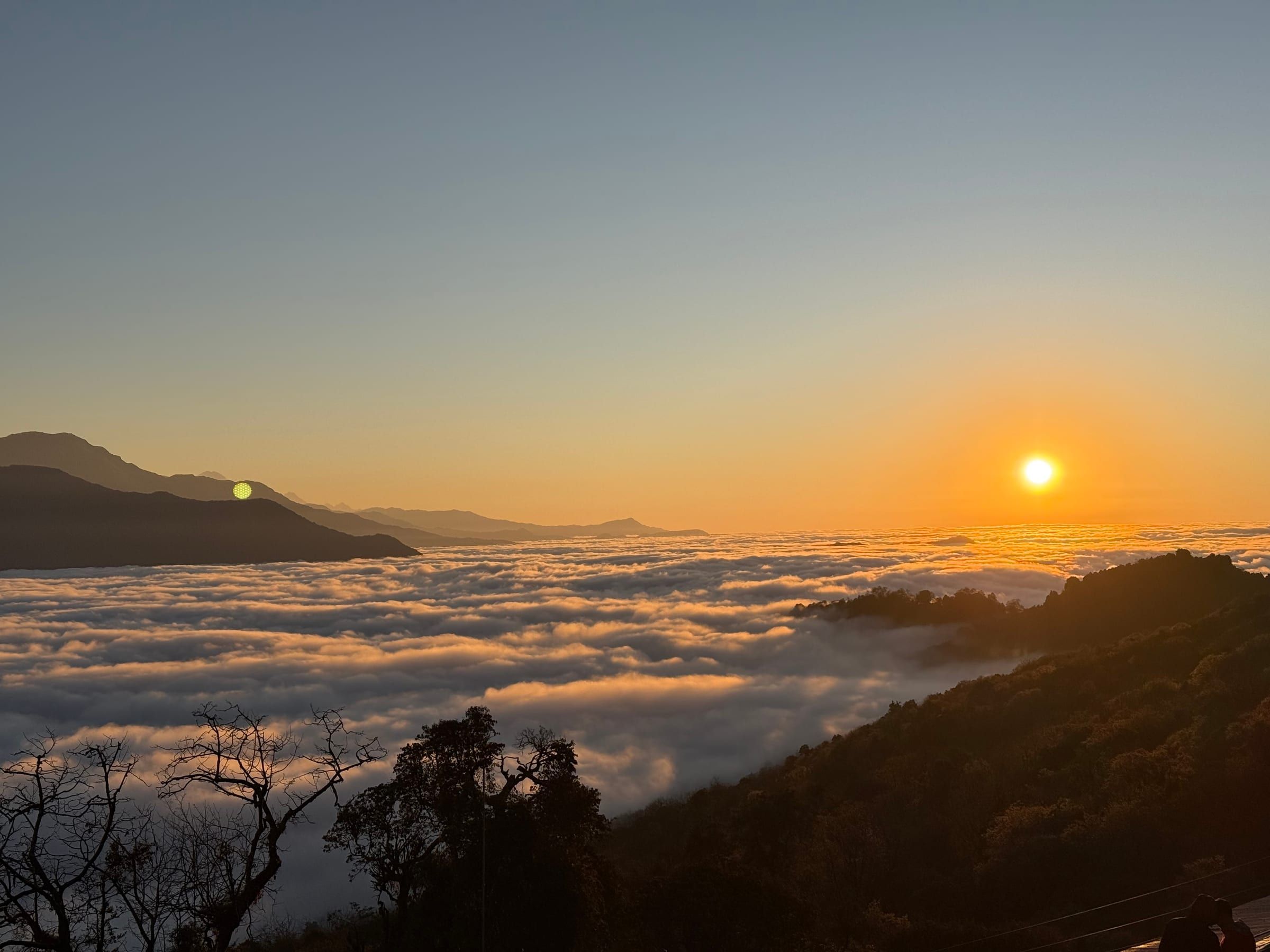 Above the clouds, golden sunrise light spreading across the peaks