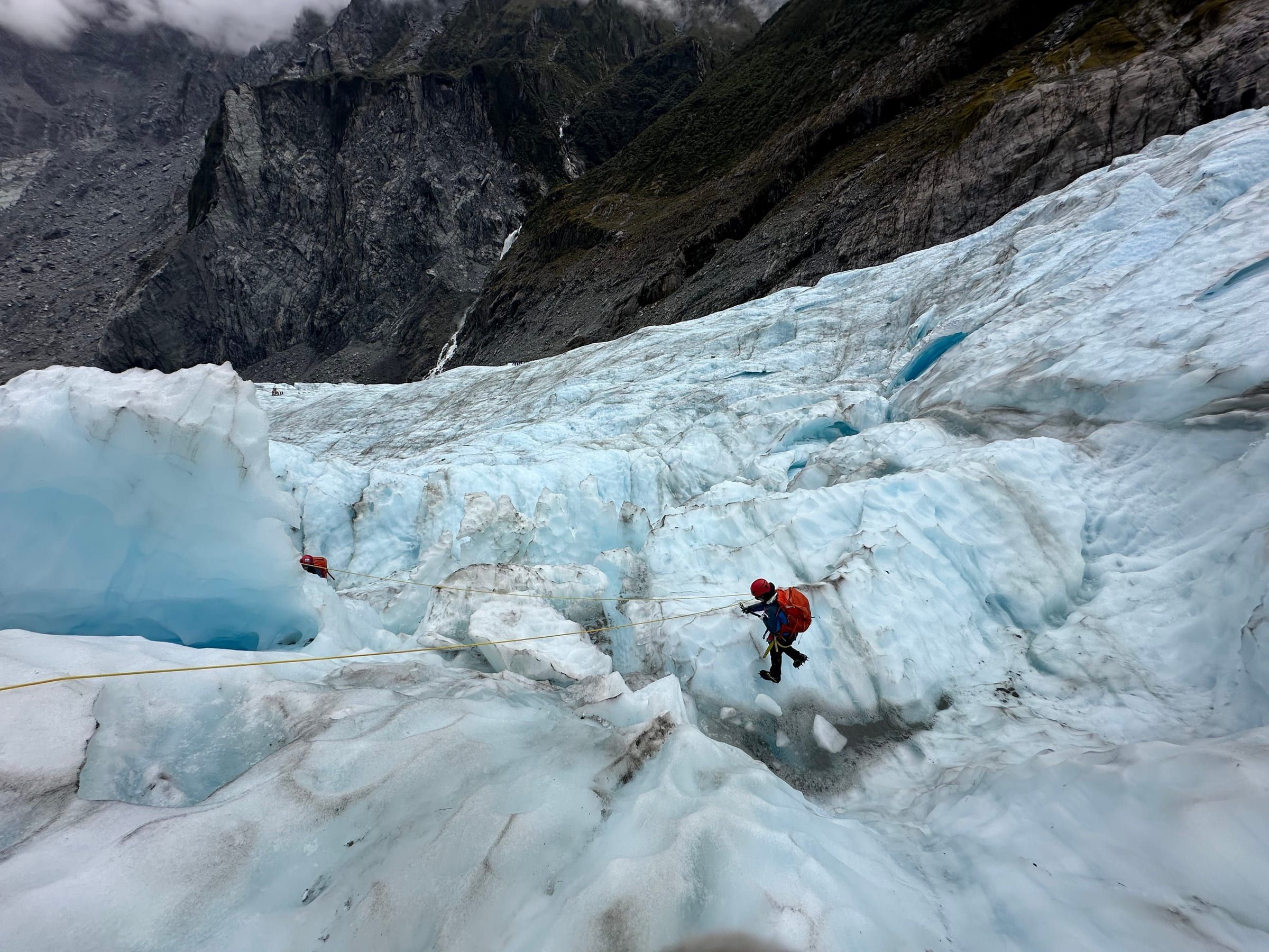 Roped up, mid-step across a crevasse on the glacier, ice stretching out in every direction