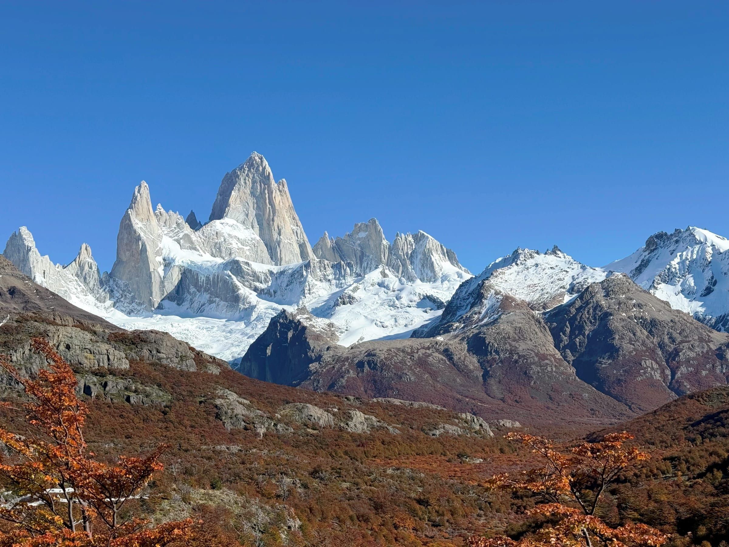 Fitz Roy massif, sharp granite spires under full daylight with autumn foliage in foreground