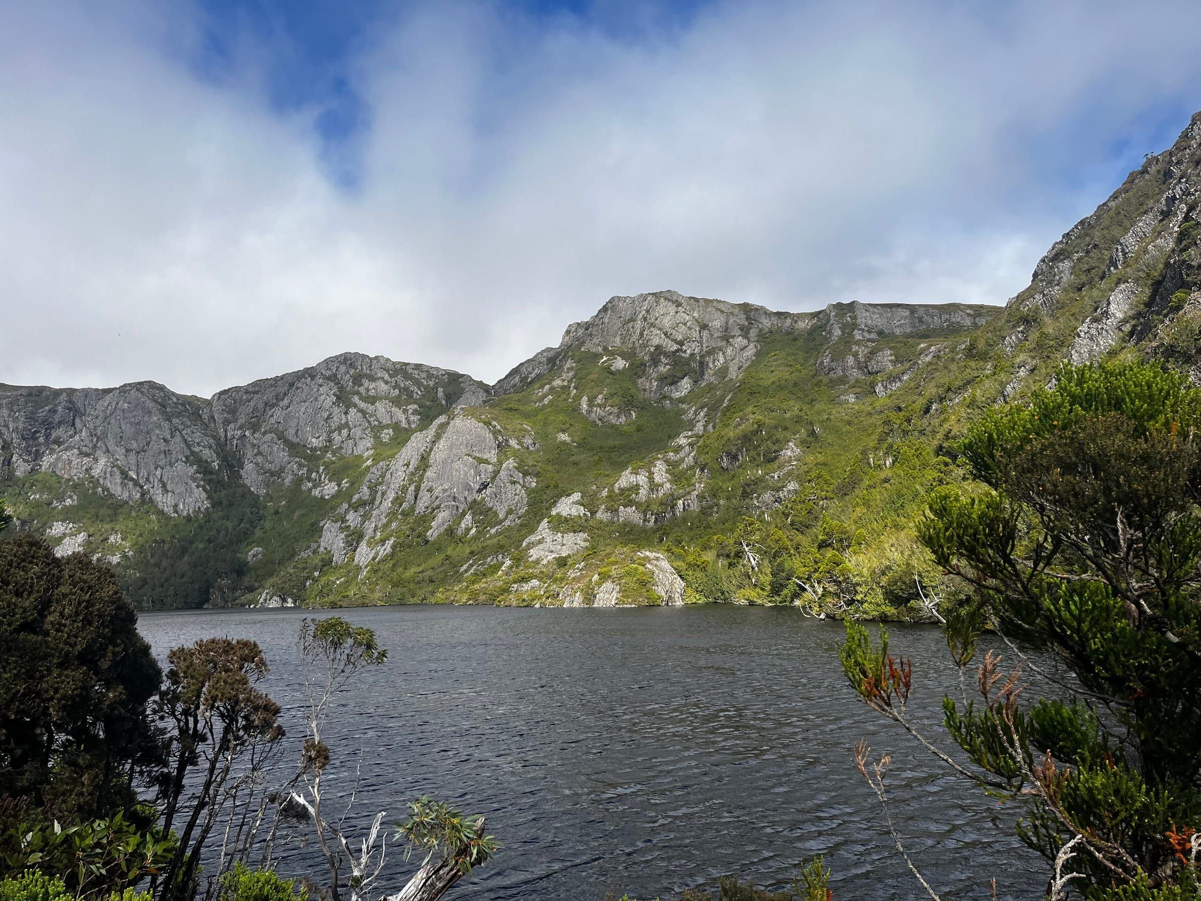 A still lake surrounded by rocky, forested mountains